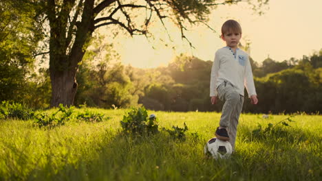 In-slow-motion-the-boy-plays-funny-with-a-soccer-ball-in-a-meadow-at-sunset